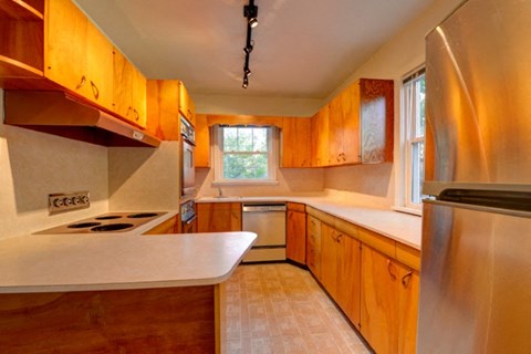 a kitchen with wooden cabinets and a stainless steel refrigerator