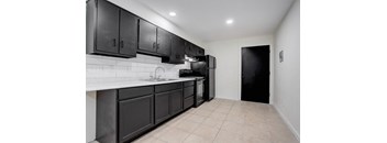 a kitchen with black cabinets and a black refrigerator