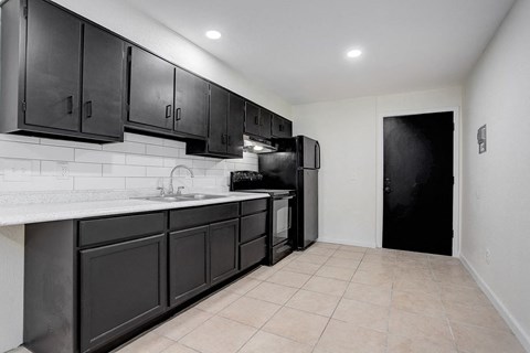 a kitchen with black cabinets and a black refrigerator
