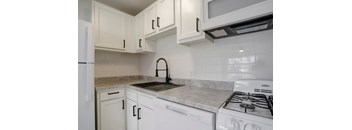 an empty kitchen with white cabinets and white appliances