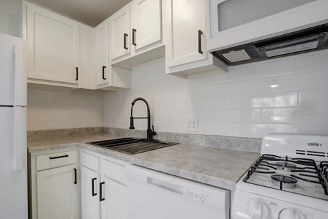 an empty kitchen with white cabinets and white appliances