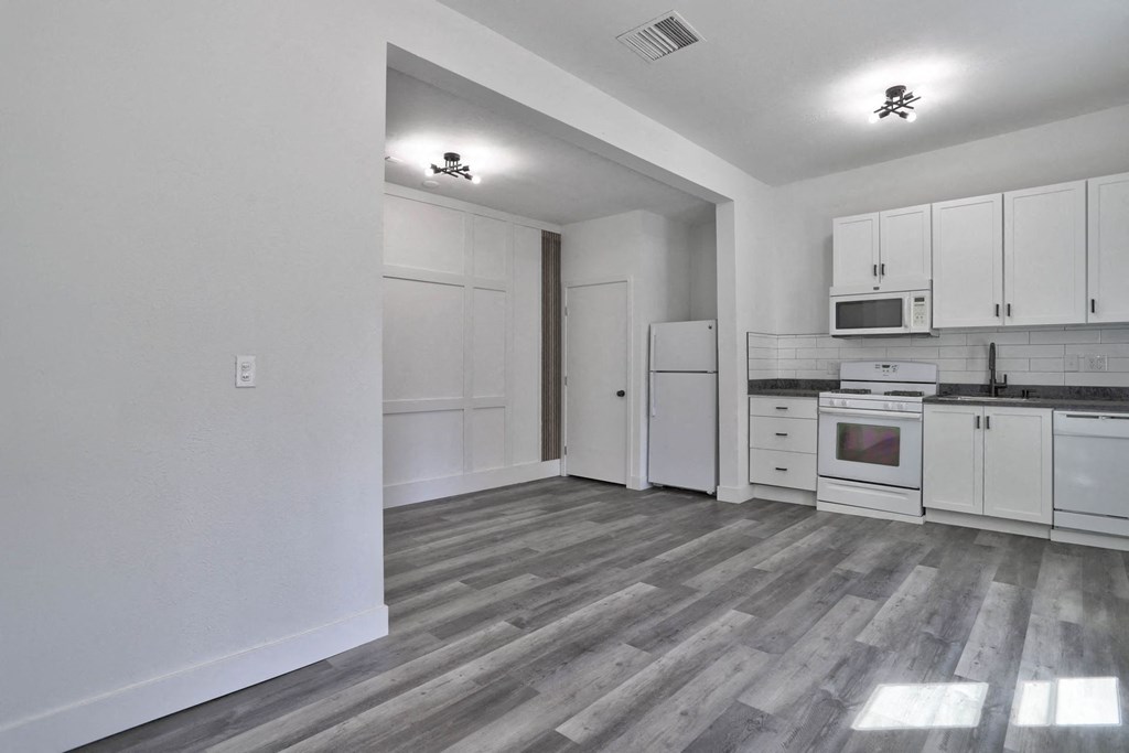 an empty kitchen with white cabinets and a white refrigerator and microwave