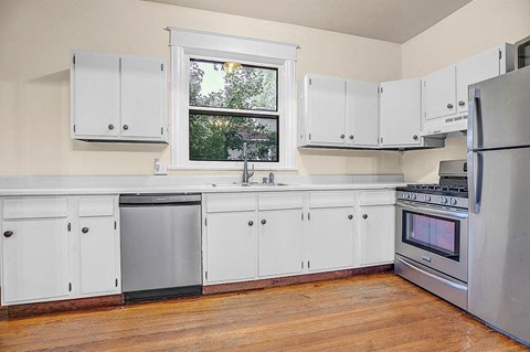 A kitchen with white cabinets and a window.