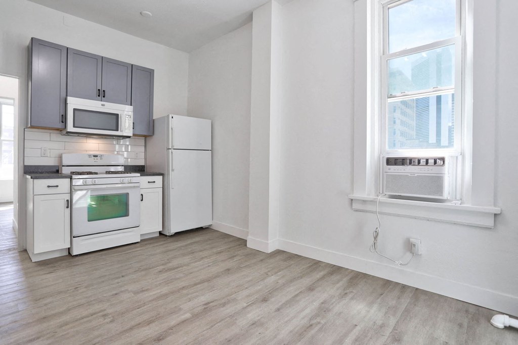 an empty kitchen with white appliances and a window