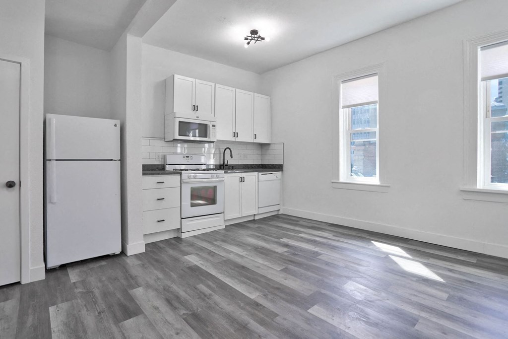 an empty kitchen with white cabinets and a refrigerator