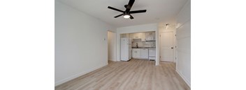 an empty living room with a ceiling fan and a kitchen