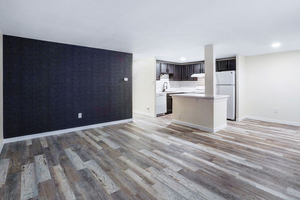 an empty living room with a kitchen in the background at The Iris Apartments, Arvada