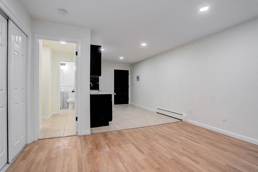 a living room with a hard wood floor and a door to a bathroom