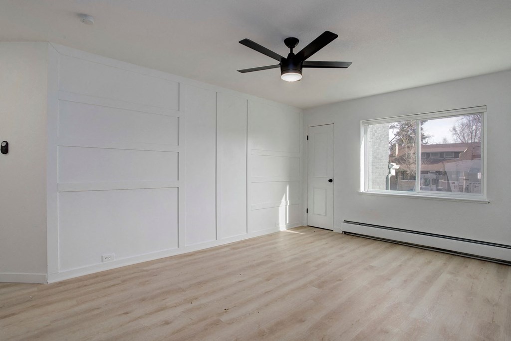 an empty living room with white walls and a ceiling fan