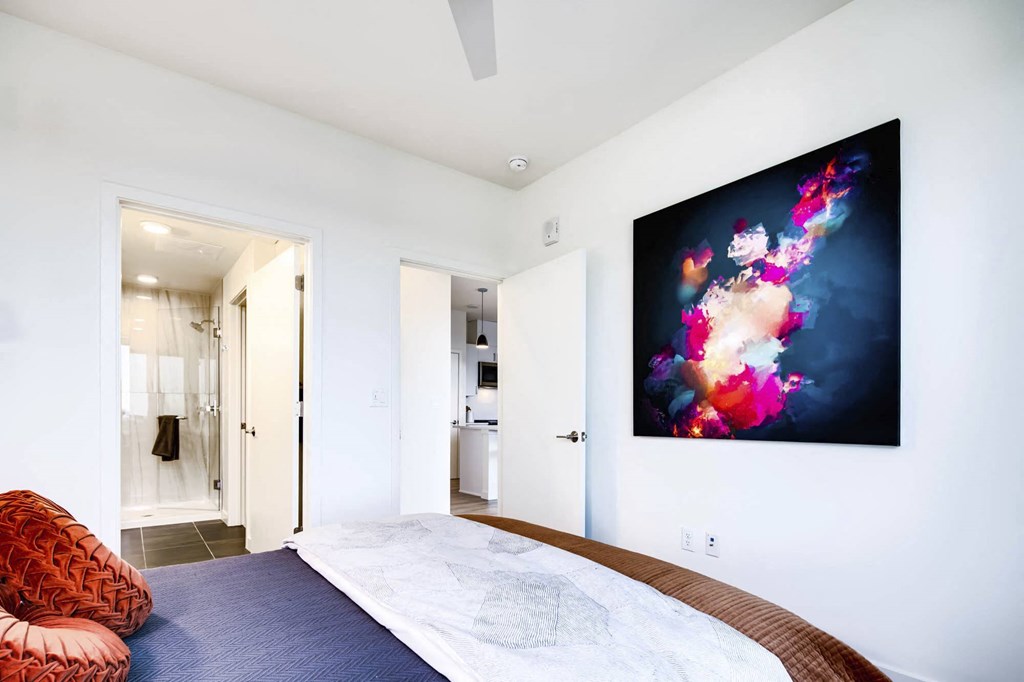 a bedroom with a large bed and a colorful painting on the wall