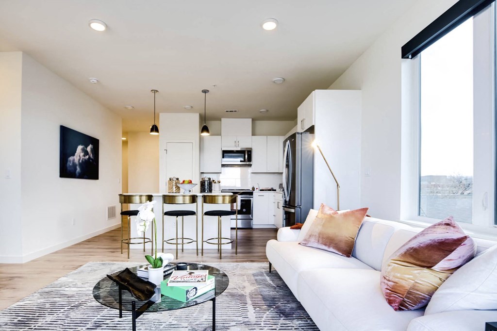 a living area with a couch coffee table and a kitchen in the background