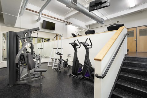 A gym with a variety of equipment including a treadmill, stationary bike, and weight bench.