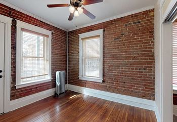 A room with a brick wall and a ceiling fan.
