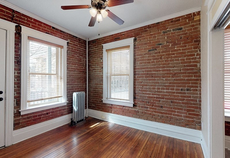an empty room with a brick wall and a ceiling fan