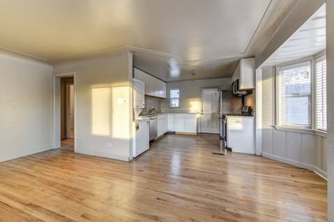 A spacious kitchen with wooden floors and white walls.