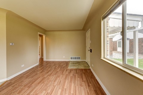 A room with wooden floors and a window overlooking a brick building.
