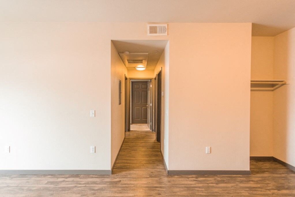 a hallway with a wood floor and white walls and a door