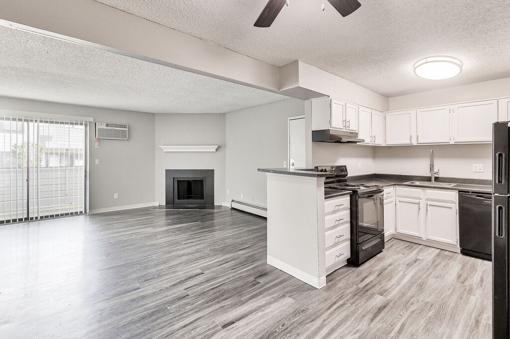 A modern kitchen with white cabinets and a black stove top oven.at Miramar Apartments, Denver Colorado