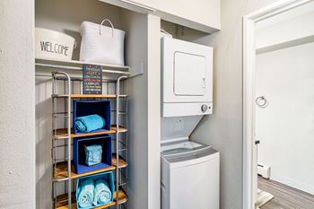 A laundry room with a washer and dryer, a sign, and a basket on top of a shelf.