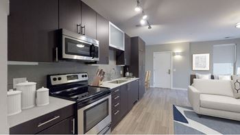 A modern kitchen with dark brown cabinets and stainless steel appliances.