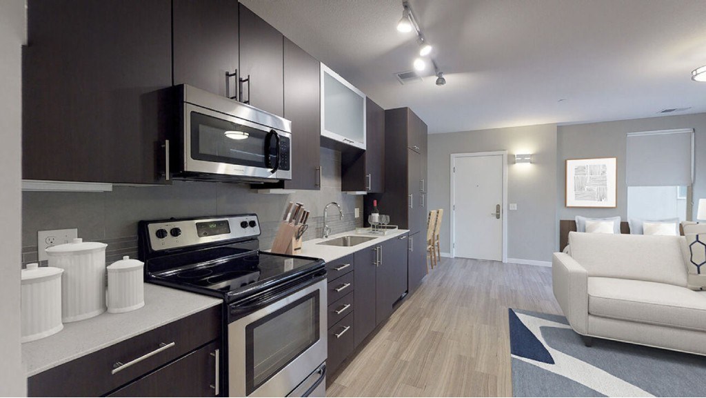A modern kitchen with dark brown cabinets and stainless steel appliances.at The Logan Apartments, Denver, CO 80203