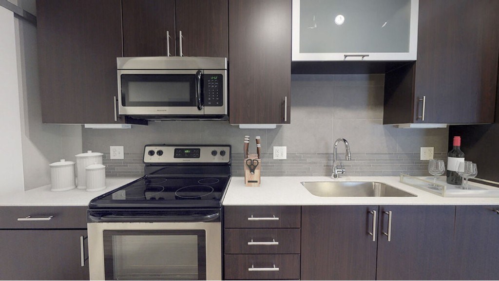 A modern kitchen with a stove, microwave, and sink.at The Logan Apartments, Denver, CO
