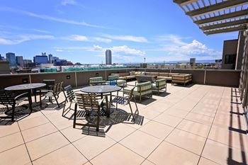 A rooftop patio with tables and chairs overlooking a city skyline.