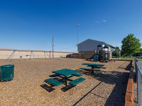 Picnic tables and a trash can are set up on a gravel field.