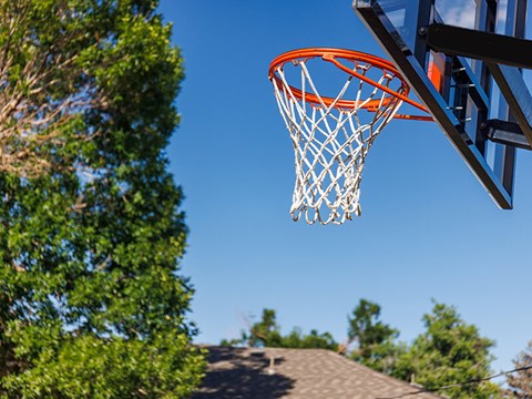 A basketball hoop with a net is seen against a clear blue sky.