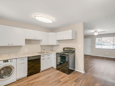 A kitchen with white cabinets and wooden floors.