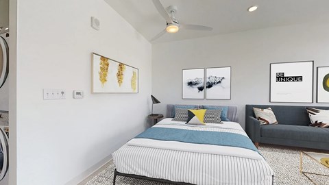 A bedroom with a bed, a couch, and pictures on the wall.