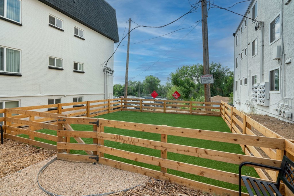 a green lawn in a wooden fence between two buildings