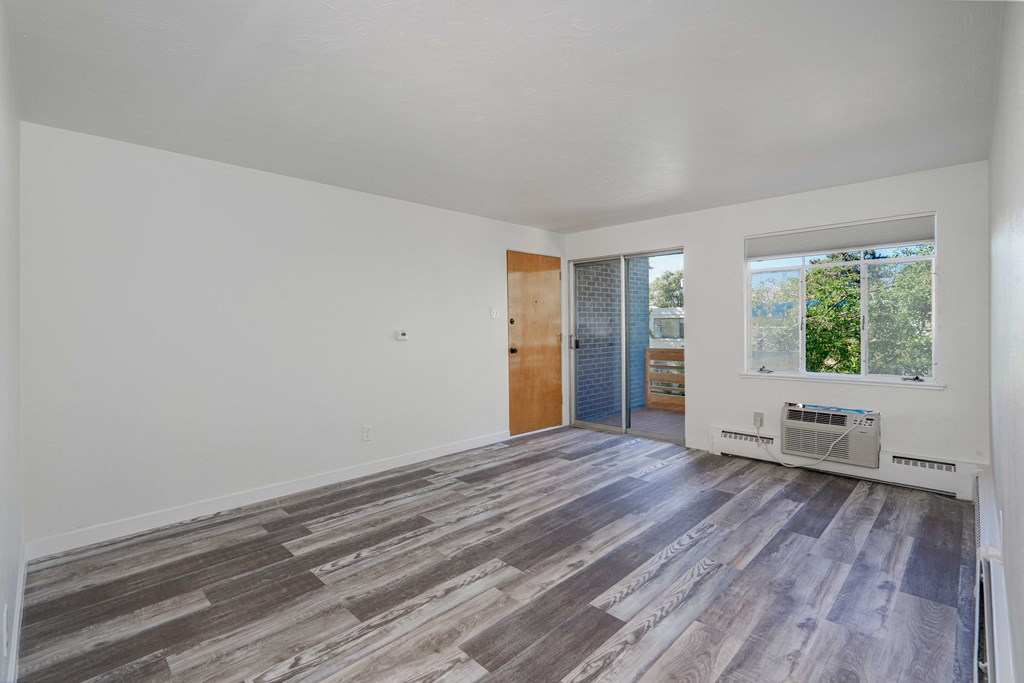 an empty living room with wood flooring and a window