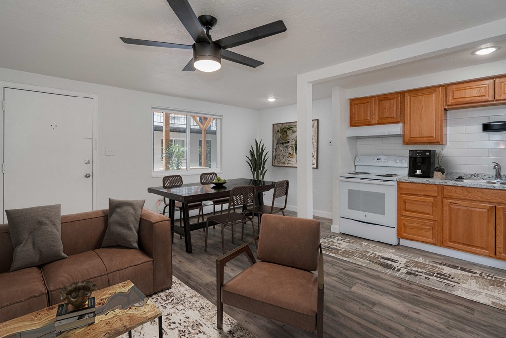 a living room and kitchen with a ceiling fan and a table with chairs