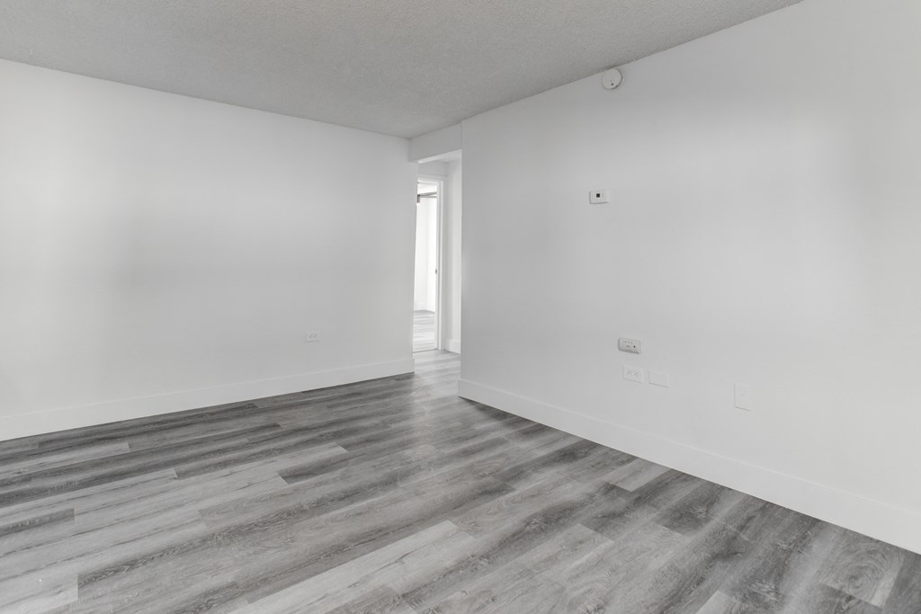 an empty room with wood floors and white walls