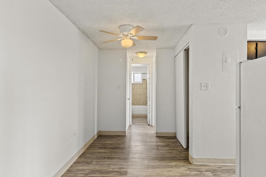 a hallway with a ceiling fan and a door to a bathroom