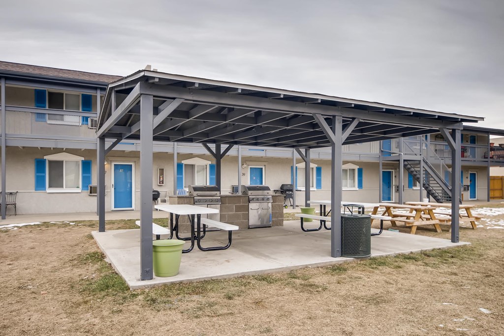 A patio area with a table and chairs is covered by a metal roof.