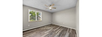 A room with a ceiling fan and wooden flooring.