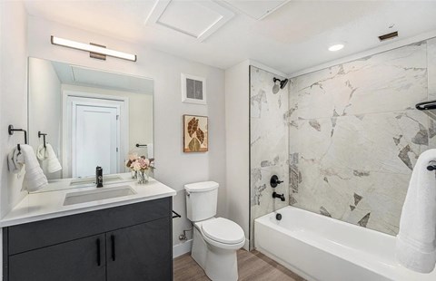 A bathroom with a marble wallpaper and a white bathtub.