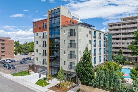 an aerial view of an apartment building with a pool and trees