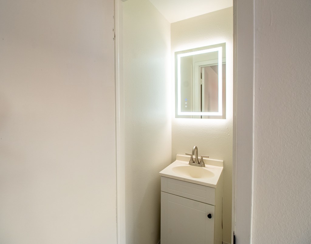 A white bathroom with a sink and mirror.