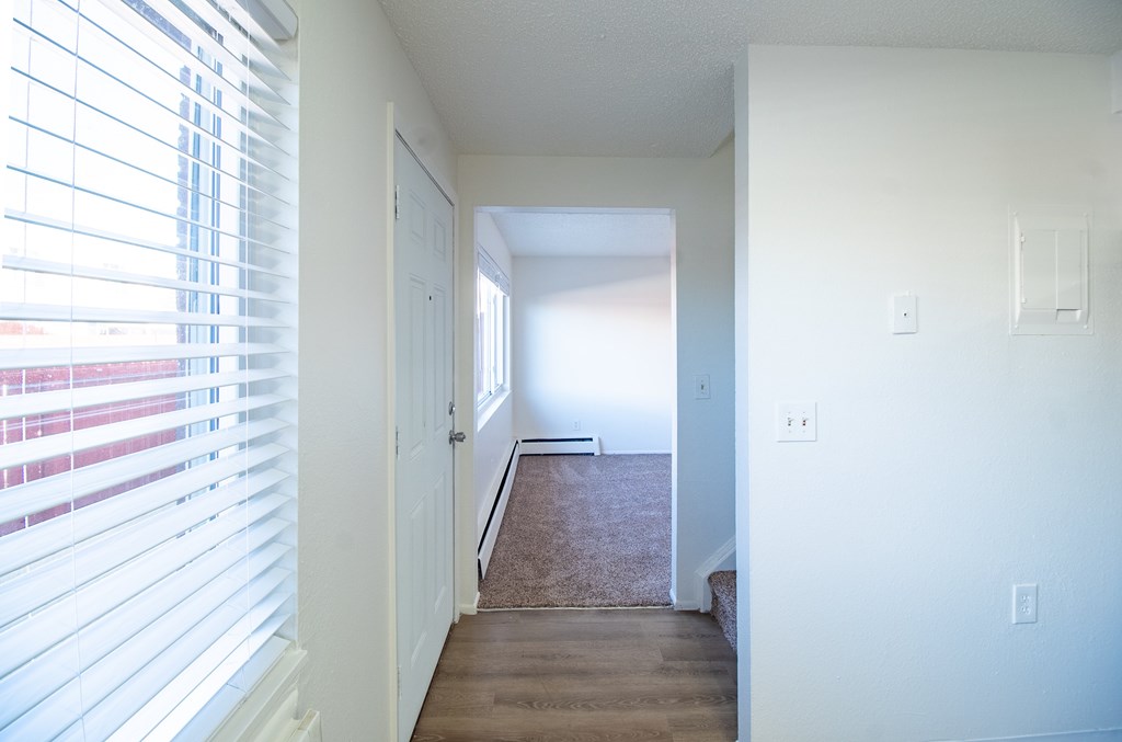 A hallway with a carpeted floor and white walls.