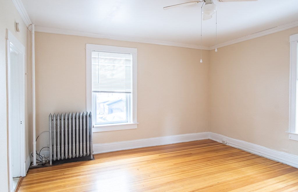A room with a window and a radiator on the floor.