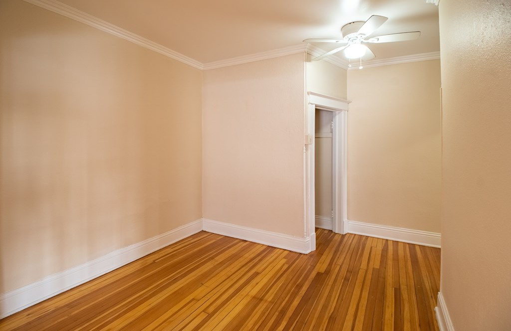 A room with wooden floors and a ceiling fan.
