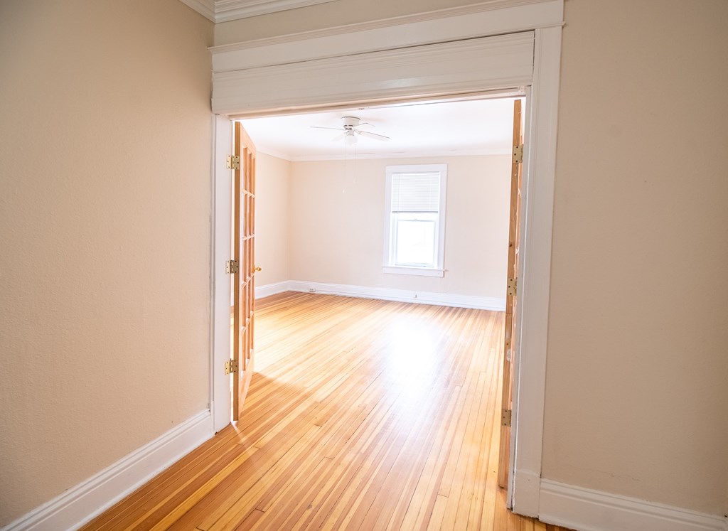 A room with a wooden floor and a doorway leading to another room.