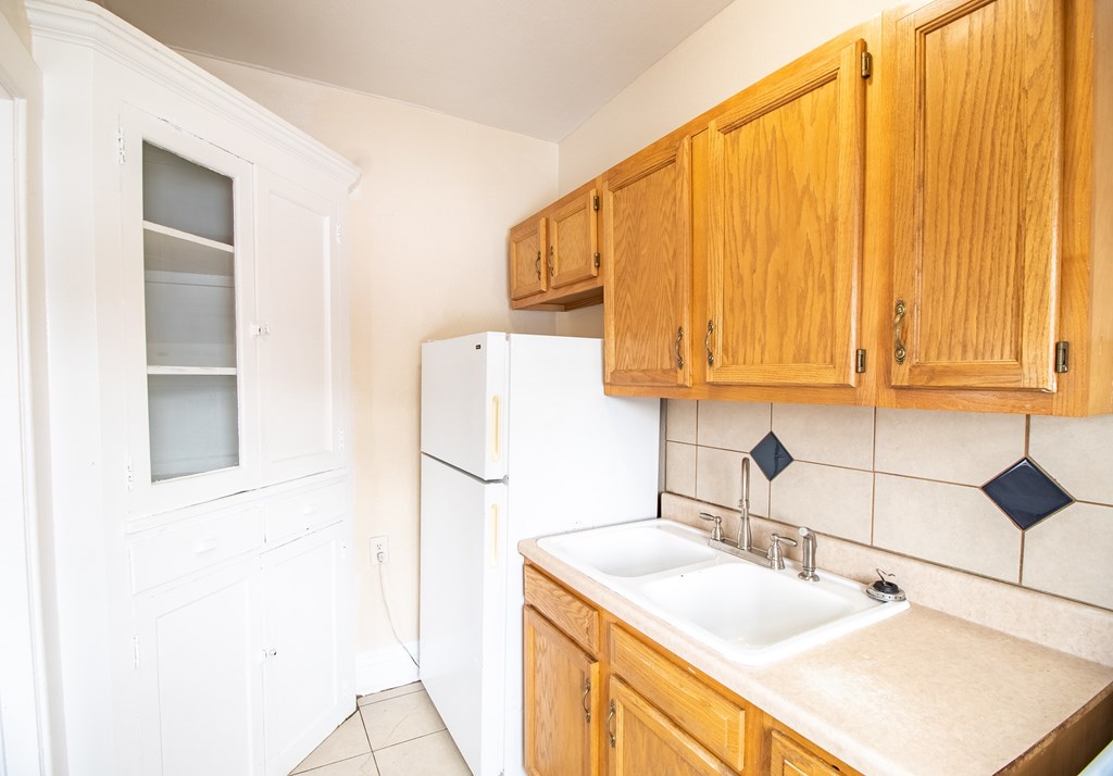 A kitchen with wooden cabinets and a white refrigerator.