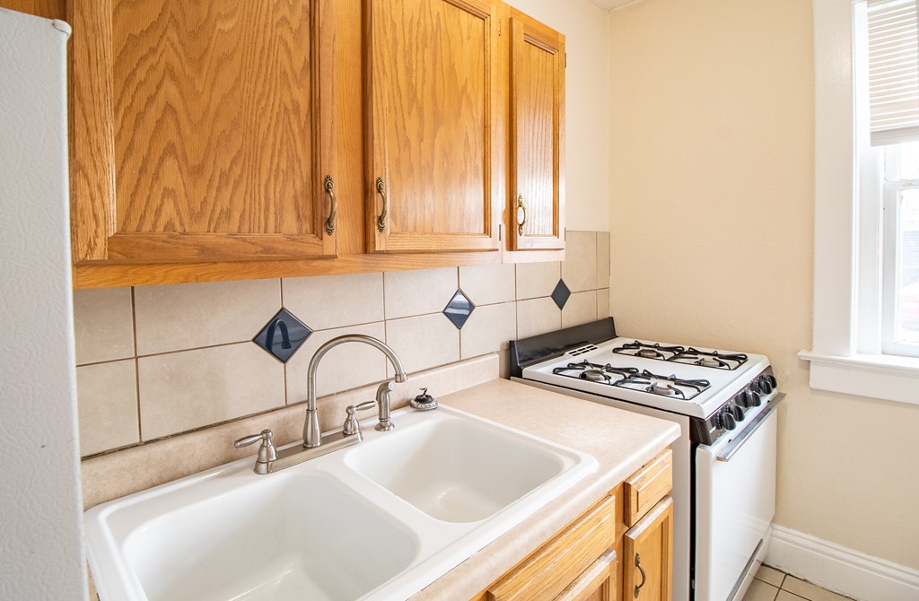 A kitchen with wooden cabinets and a white sink.