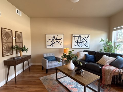 A living room with a couch, chair, and two abstract paintings on the wall.