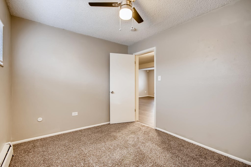 A room with a ceiling fan and carpeted floor.