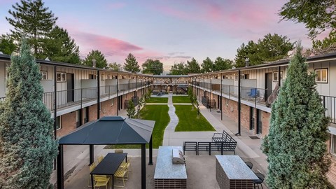 A sunset view of a courtyard with a picnic table and benches.
